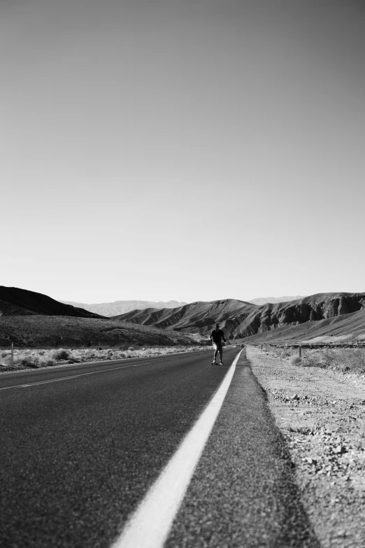 man on a bike riding down the road through the desert