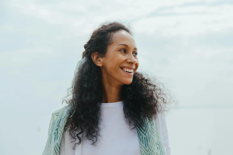 smiling woman with dark hair standing in front of a cloudy sky