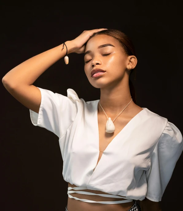 woman posing wearing a white cropped shirt and silver jewelry