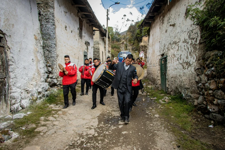 several men carrying drums walking down a street