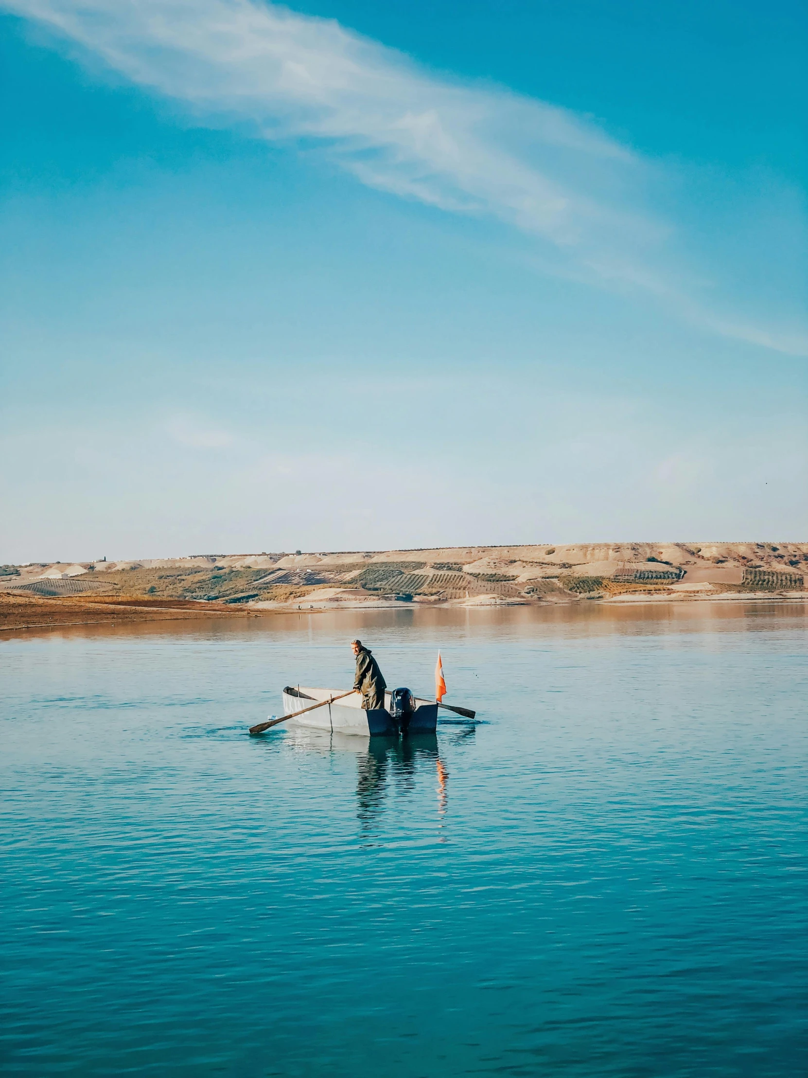 man rowing a boat on calm blue lake