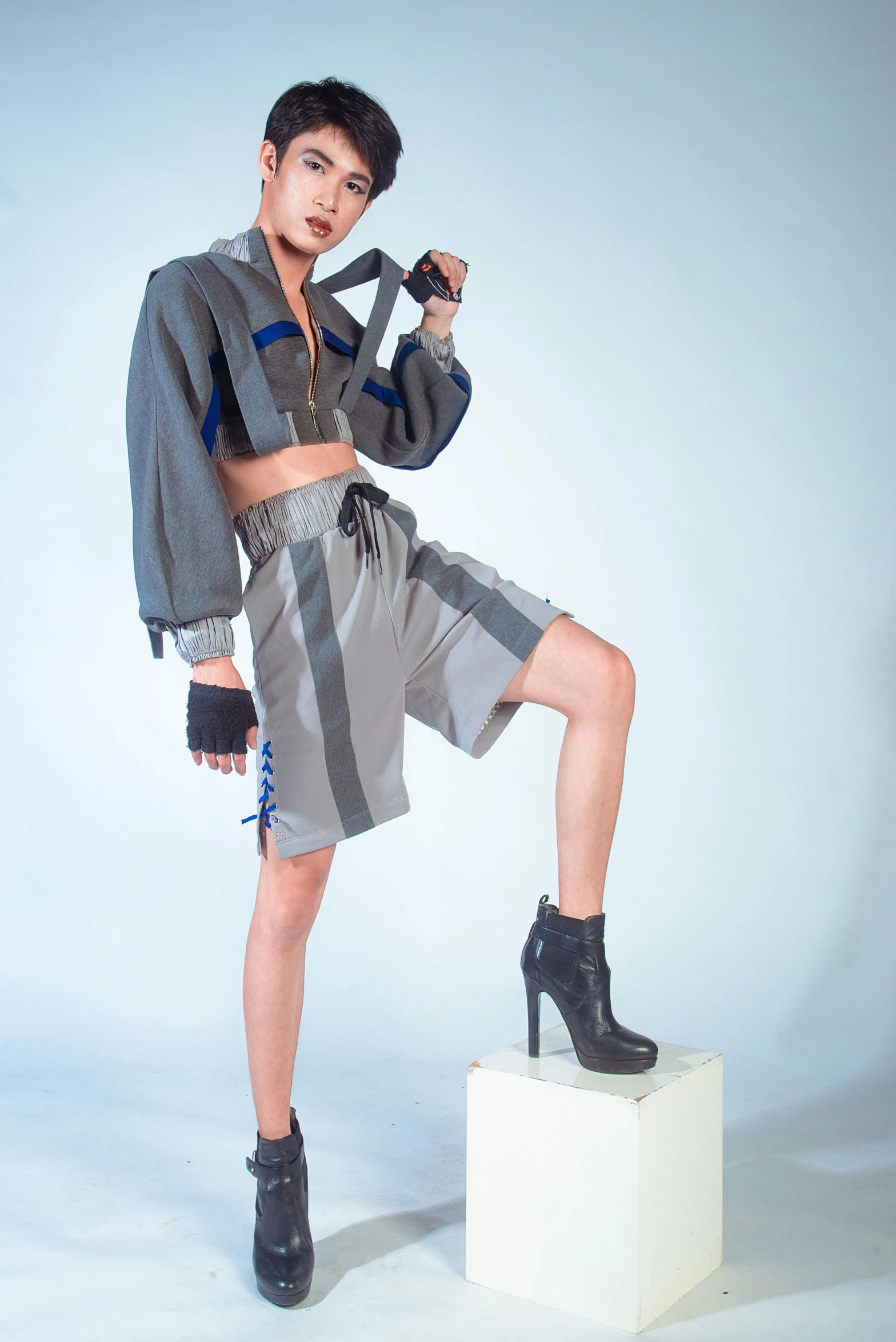 a woman poses on a white pedestal wearing a dress and jacket