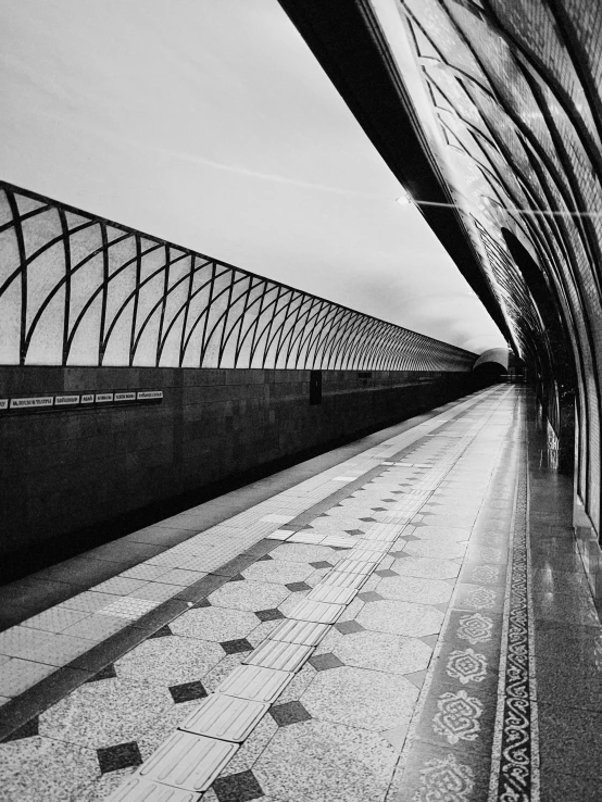 a black and white po shows the empty walkway at a train station