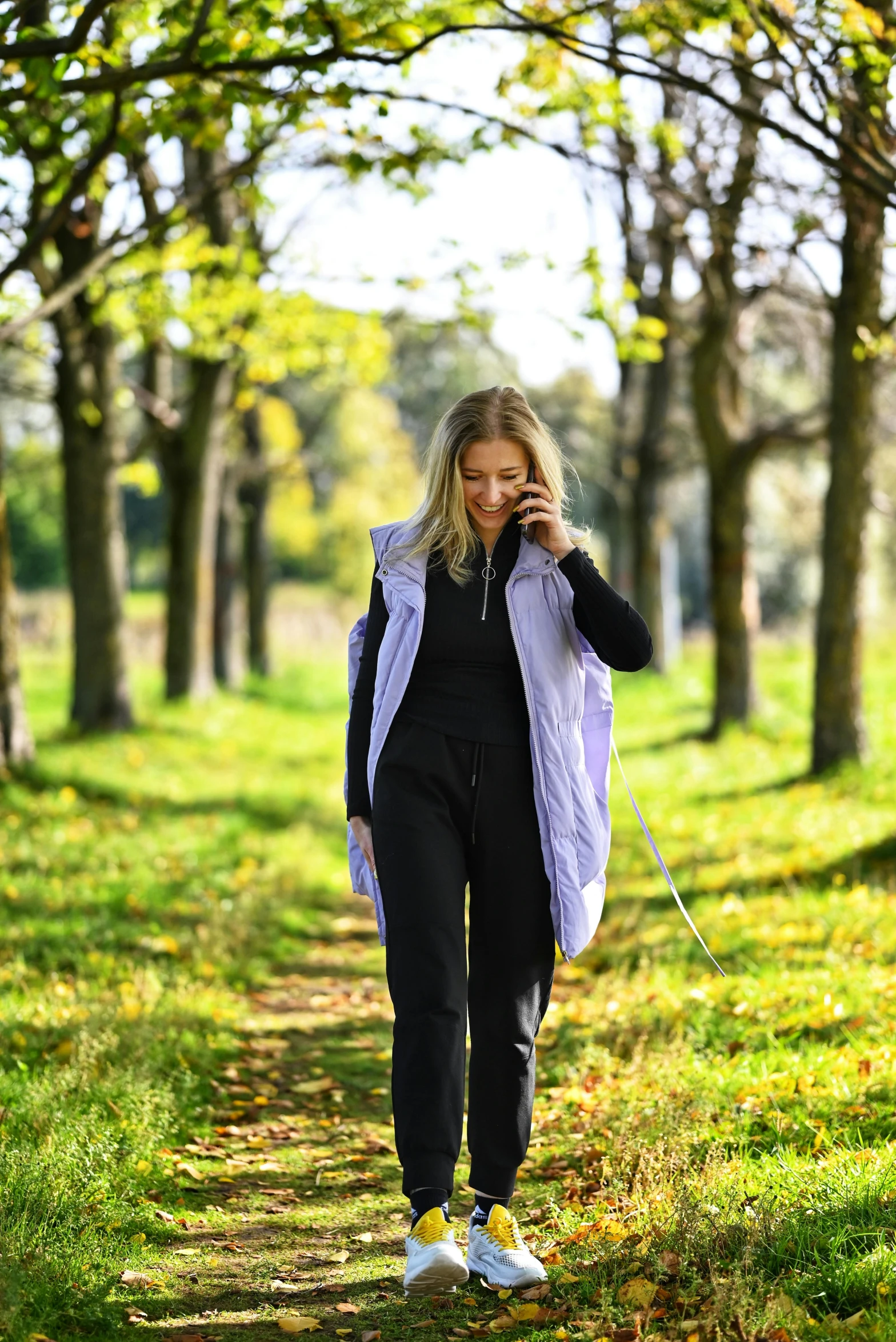 a woman walking through the park talking on her cell phone