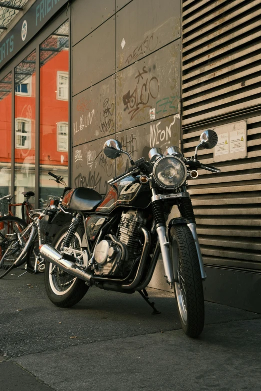 a motorcycle parked on the sidewalk beside graffiti