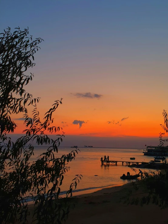 a beautiful sunset at a beach with several boats docked