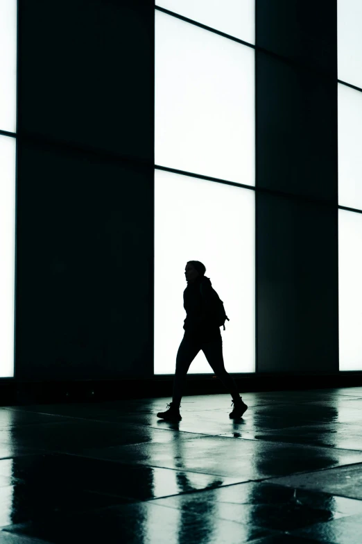 person walking near tall windows and looking through glass