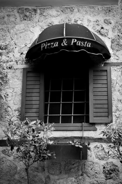 a black and white image of an outside store front with a window