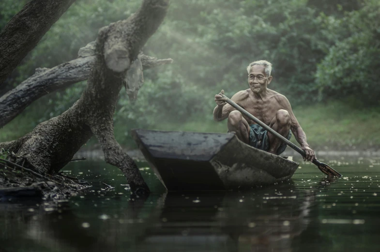 an elderly man rowing a canoe in a river