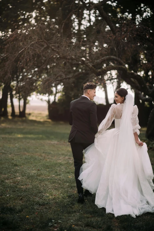 a bride and groom are standing by some trees