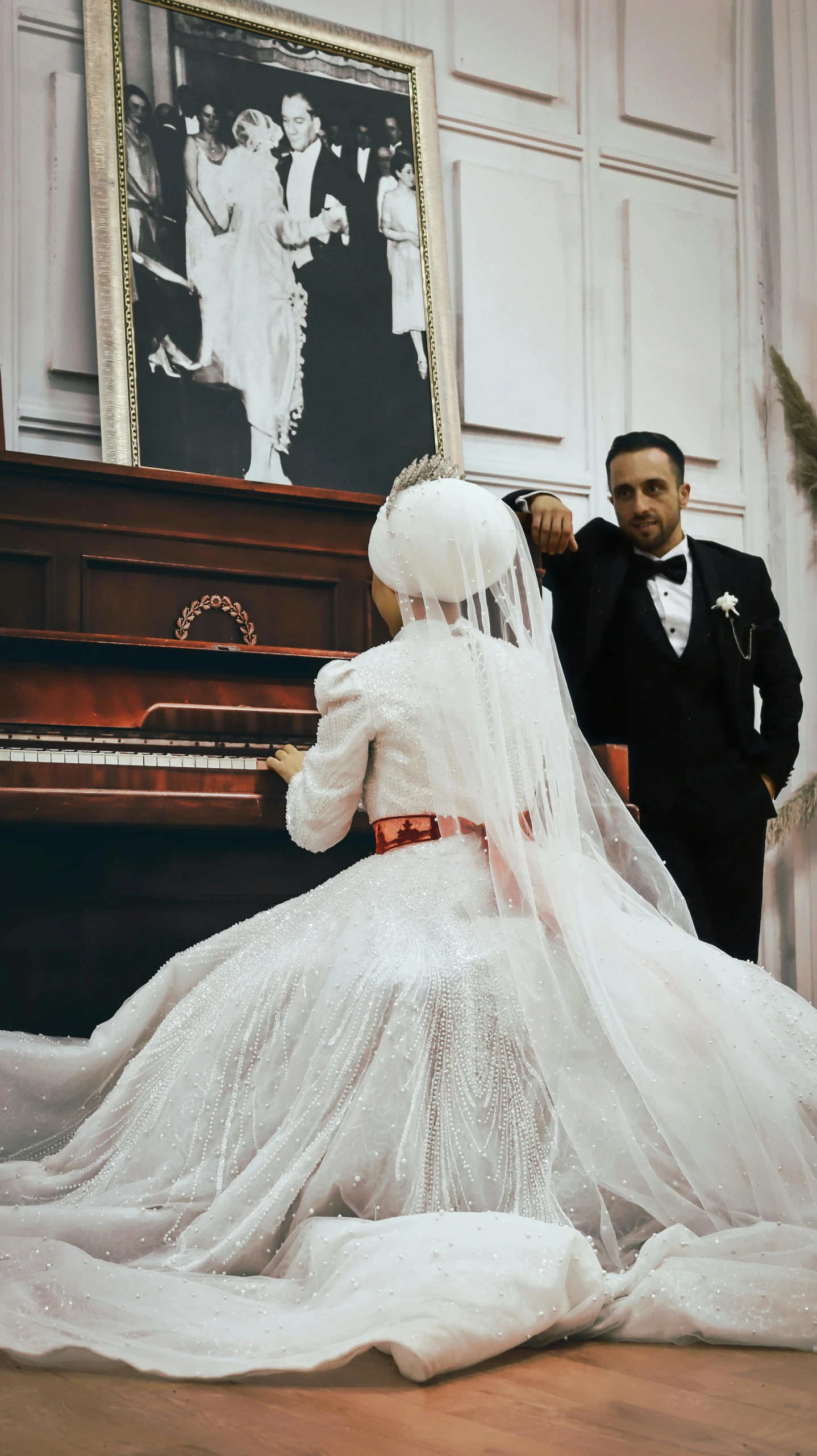 a bride is standing beside a piano with her veil on