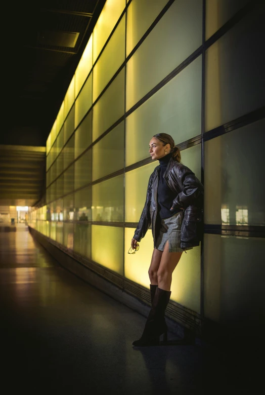 woman with black boots standing in front of a window at night