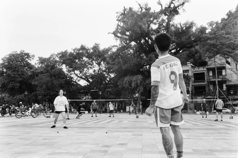 black and white pograph of man playing tennis on brick floor