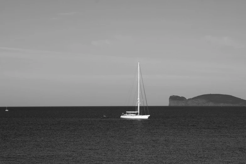 sailboat on calm sea with cliffs in background