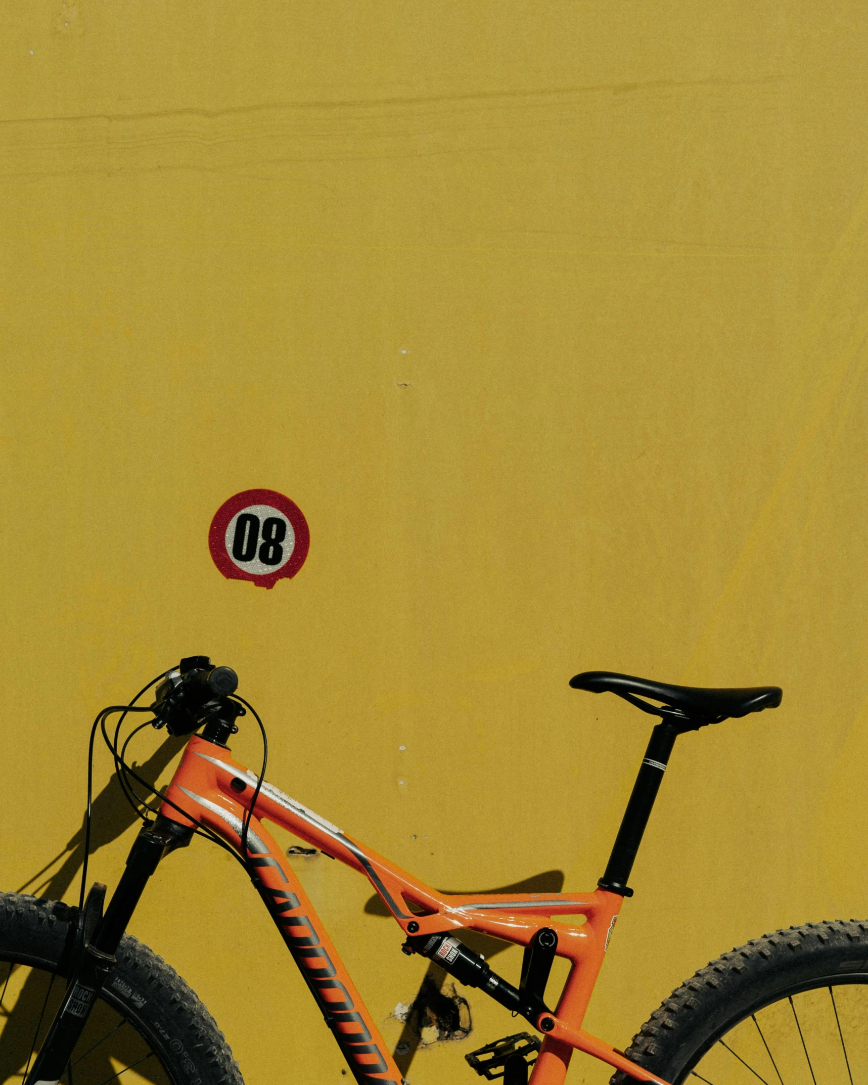 a bike leaning against a yellow wall with the number 98 on it