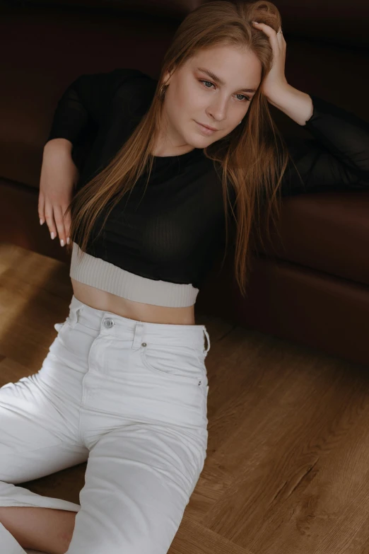 a woman sitting on the floor in white pants