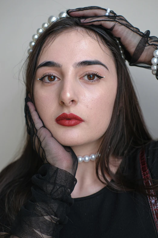 woman with dark brown hair and red lipstick, wearing sheer gloves