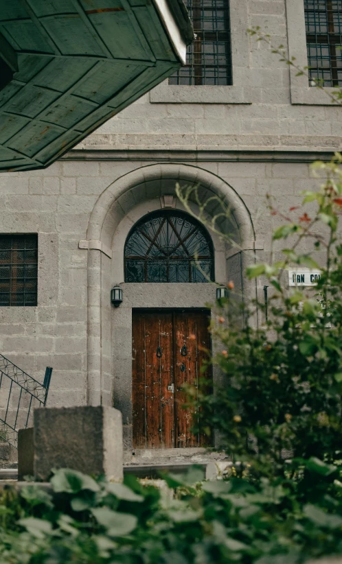 a building with two wooden doors and iron railing