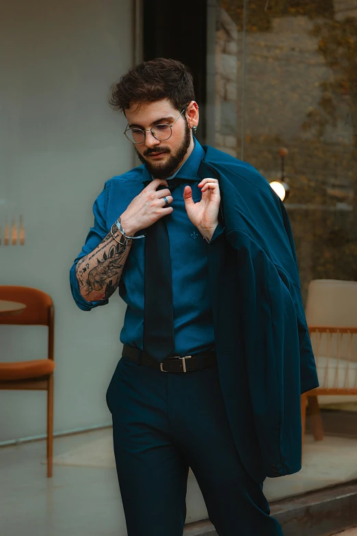 man in black slacks, blue shirt, tie and coat