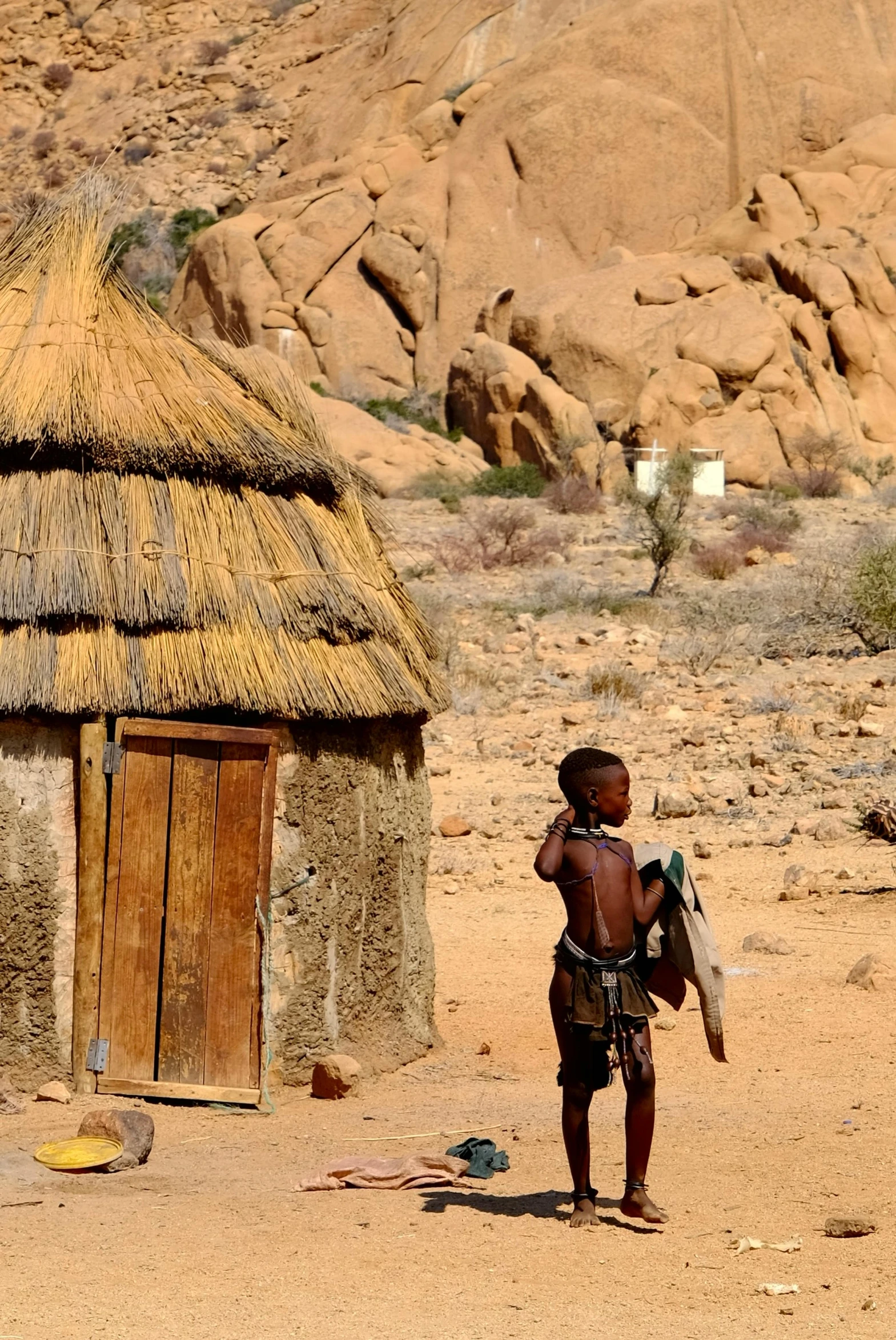 a  with a baby standing in front of a hut