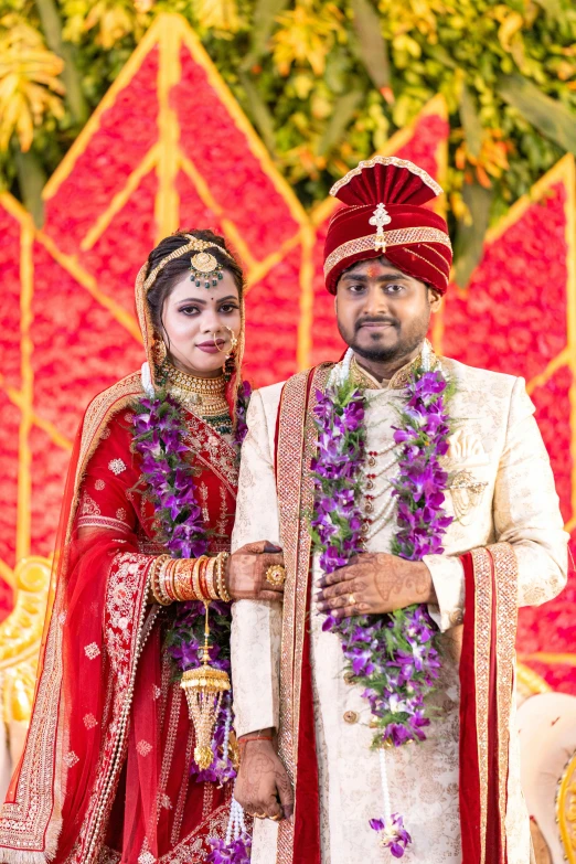 a couple wearing colorful wedding attire posing for a pograph