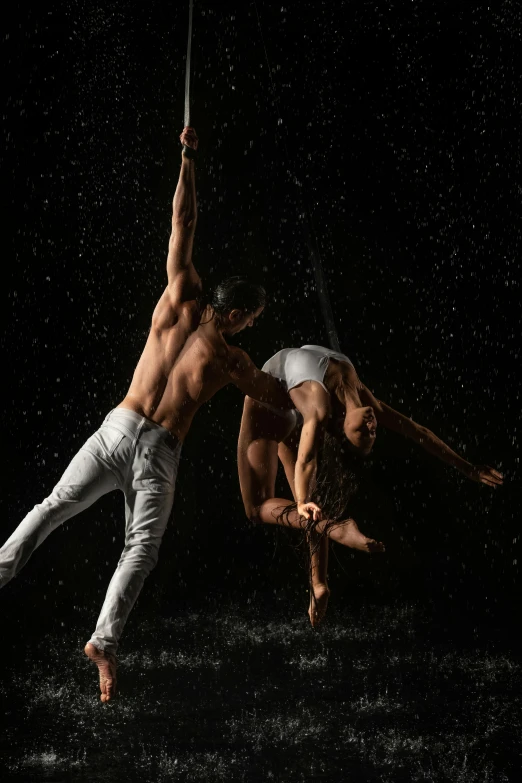 two men performing acrobatic aerial aerial tricks in the rain