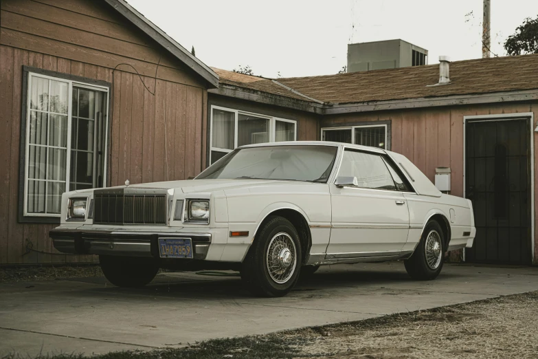 a vintage car parked in a driveway with a garage door open