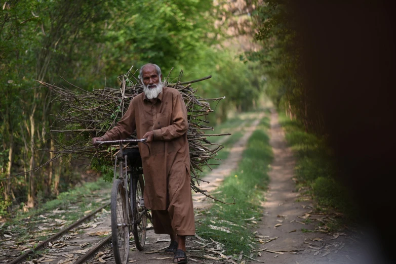 a man that is walking next to his bicycle with twigs