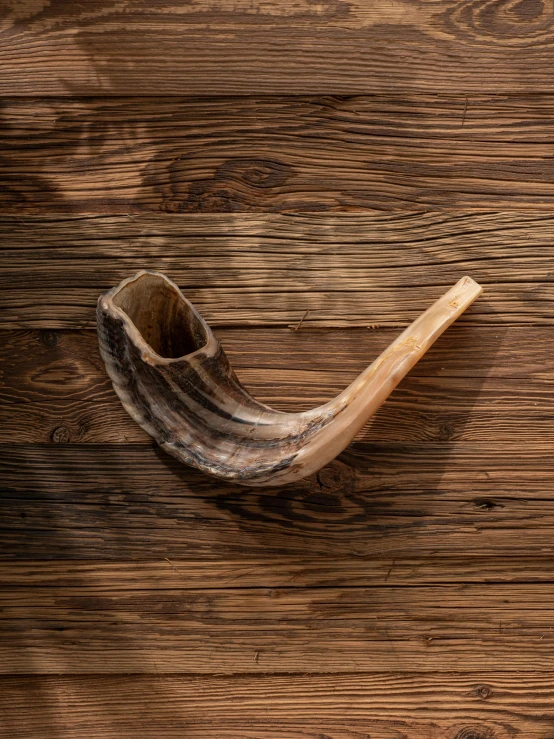 a wooden pipe with an aged, worn out handle on a wood background