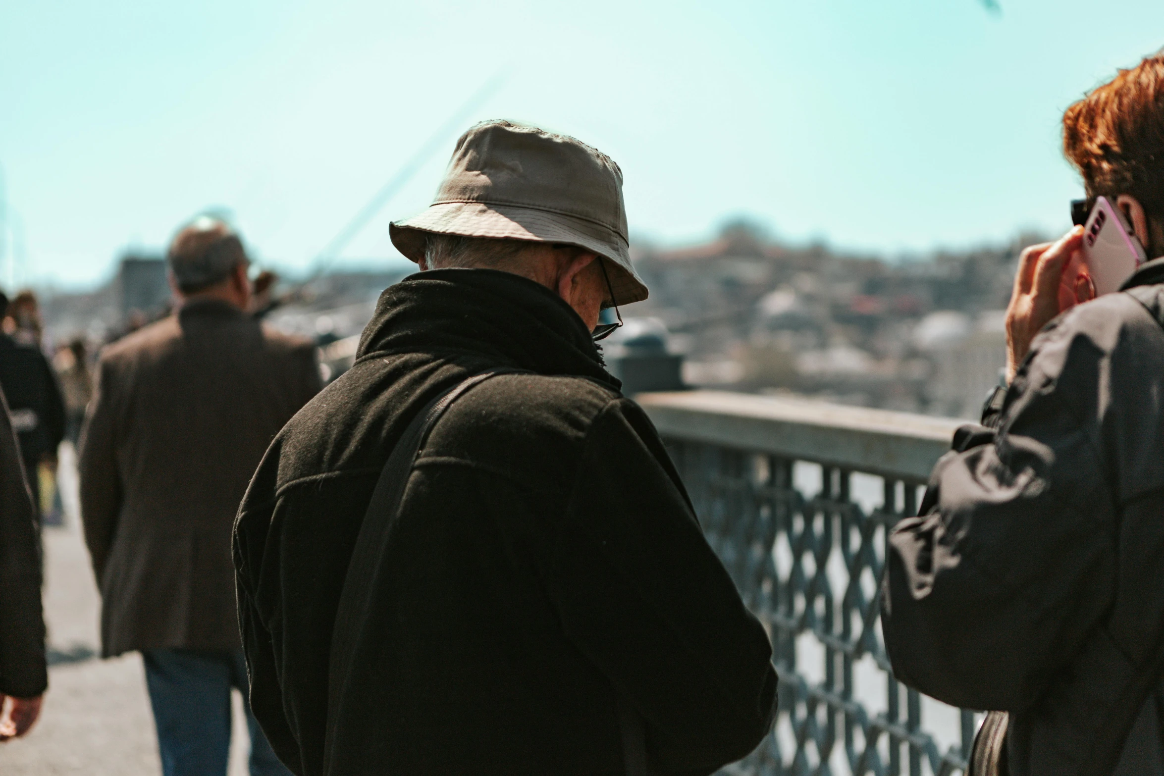 a man in a hat standing on a bridge while talking on a phone