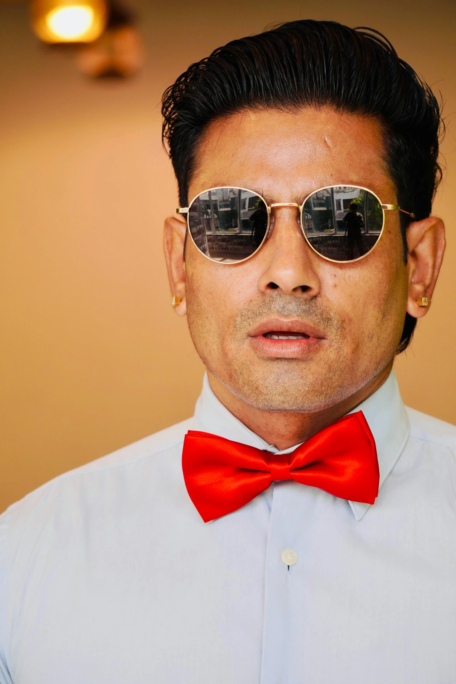 man with sunglasses on a white shirt wearing red bow tie