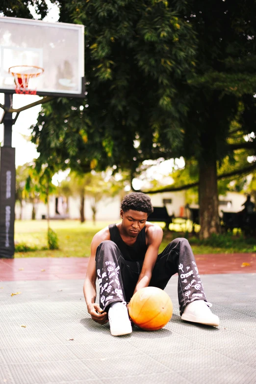 a person sitting on the ground with an orange ball in front of him