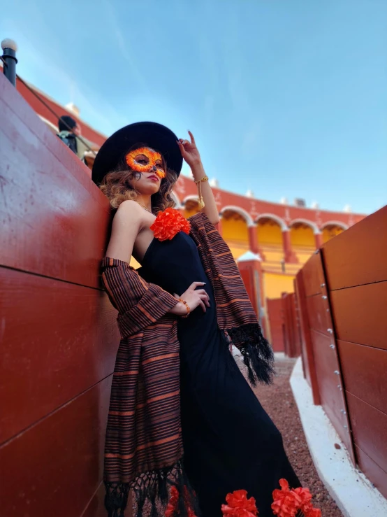 a woman wearing an elaborate black dress, red flowers and a scarf