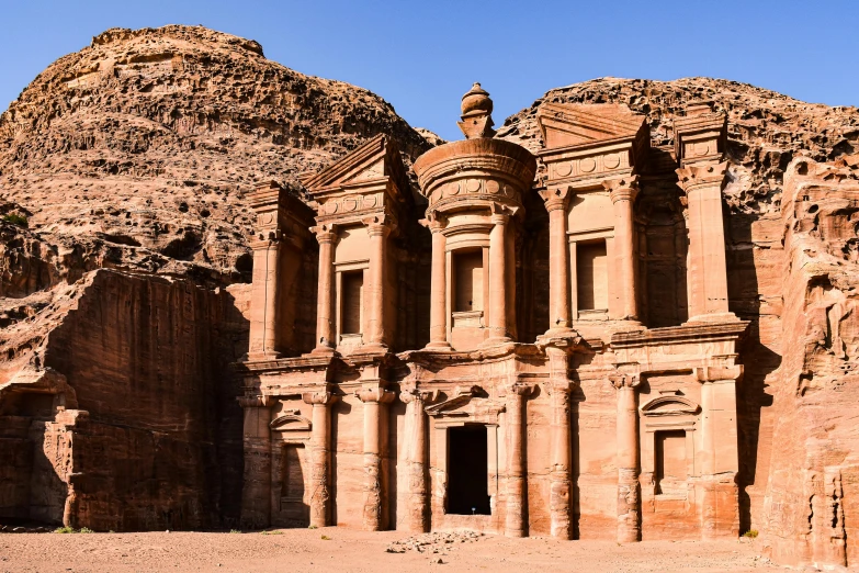 a building made out of rock and surrounded by mountains