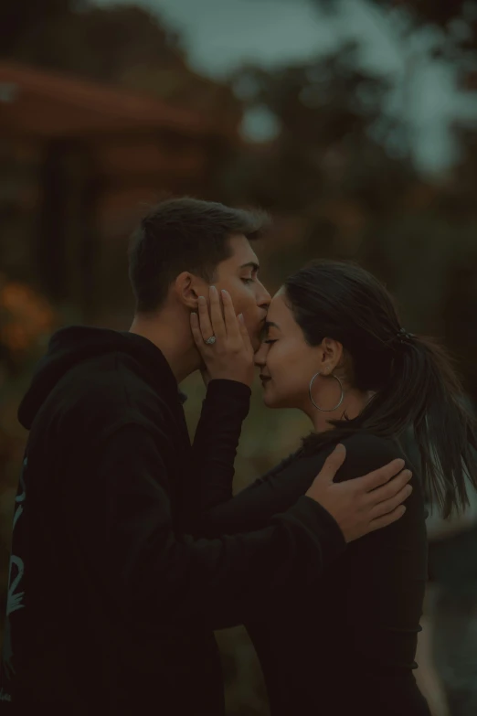 two people standing close to each other, one kissing the other