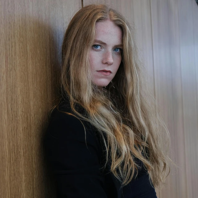 a woman standing against a wall with her head on her arm