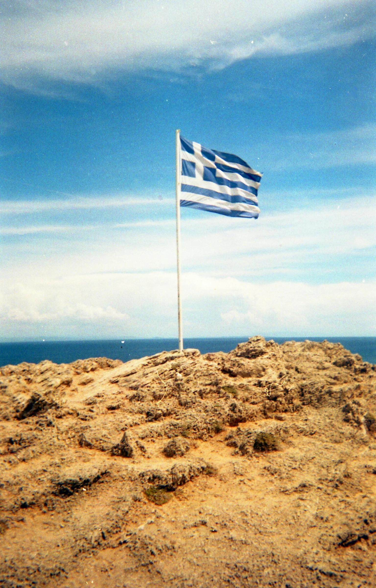 a large white and blue flag is on the side of a hill near a body of water