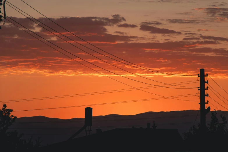 the power lines and telephone poles are silhouetted against a red sky