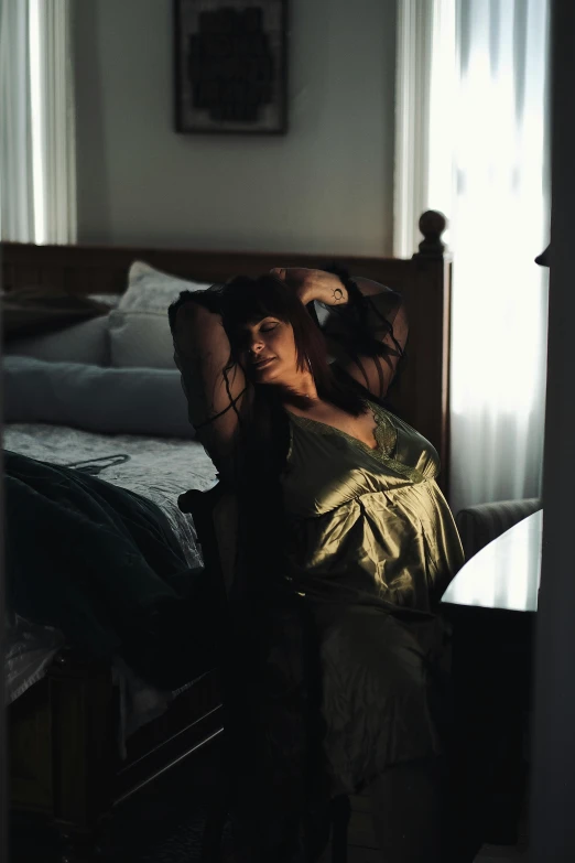 a woman wearing a long golden dress sits on a bed