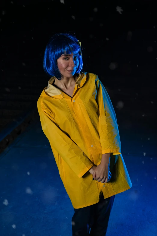 a woman in a rain coat smiling with snow falling all around her