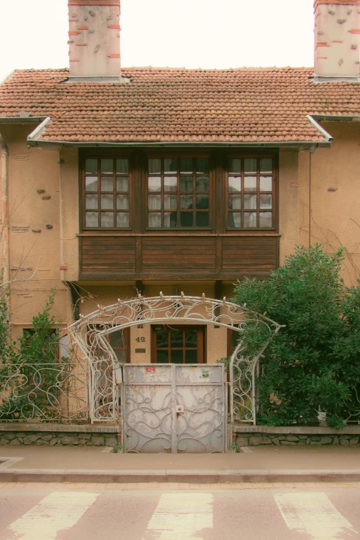 an iron gate outside of a tan brick house