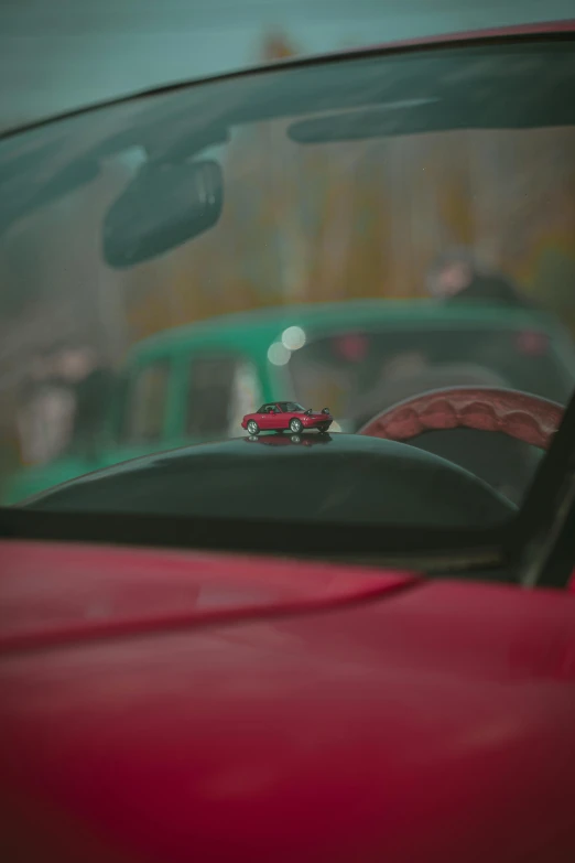 a red toy car on a road behind a car