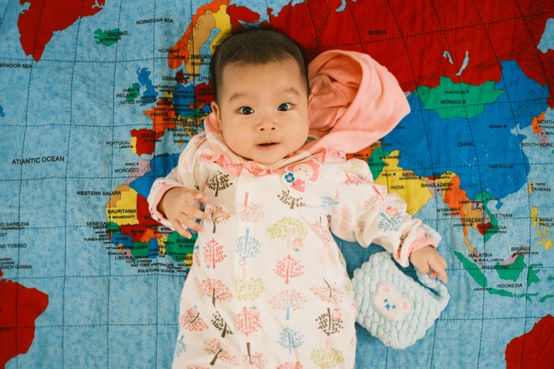 a baby with large  and a pink cap in a white dress