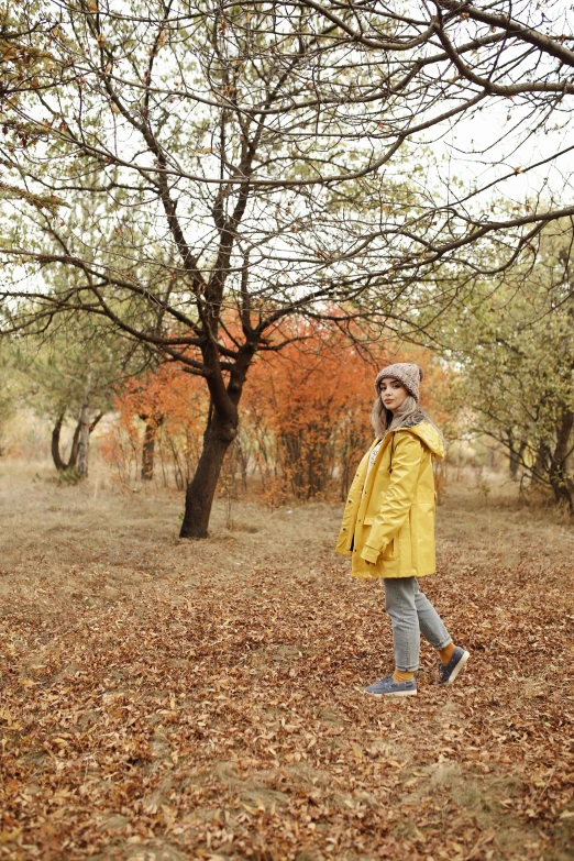 the young person is walking through the leaf strewn woods