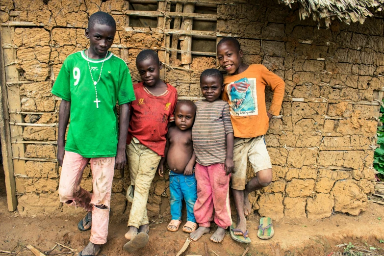 a group of s posing for a po in front of a hut