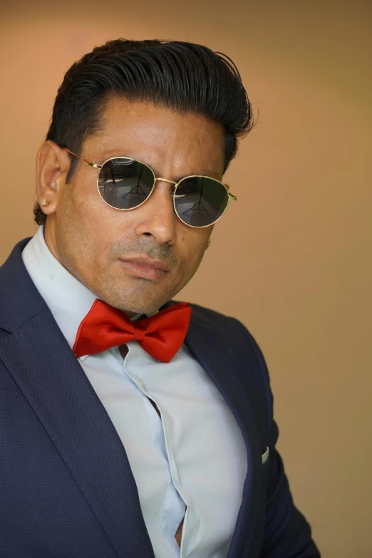 an indian man wearing a suit and red bow tie