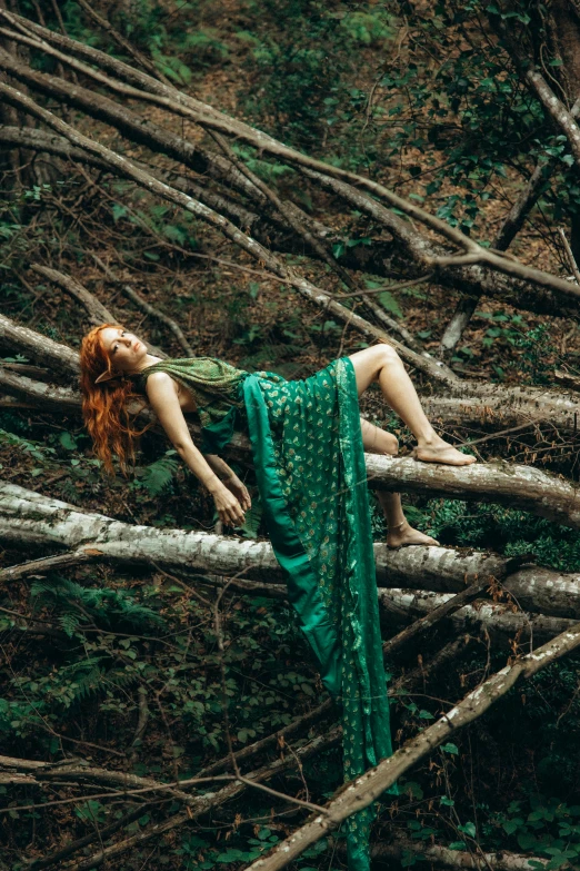 a woman laying on a tree log in the woods