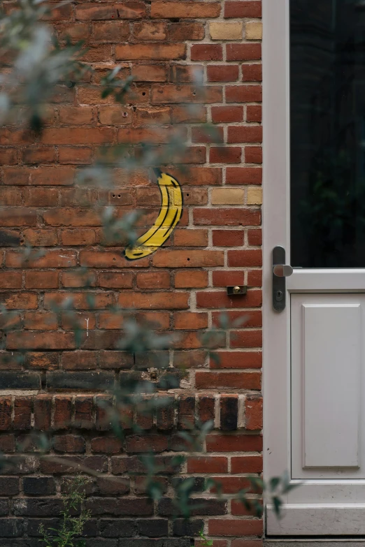 a banana painted on a brick wall with an open window