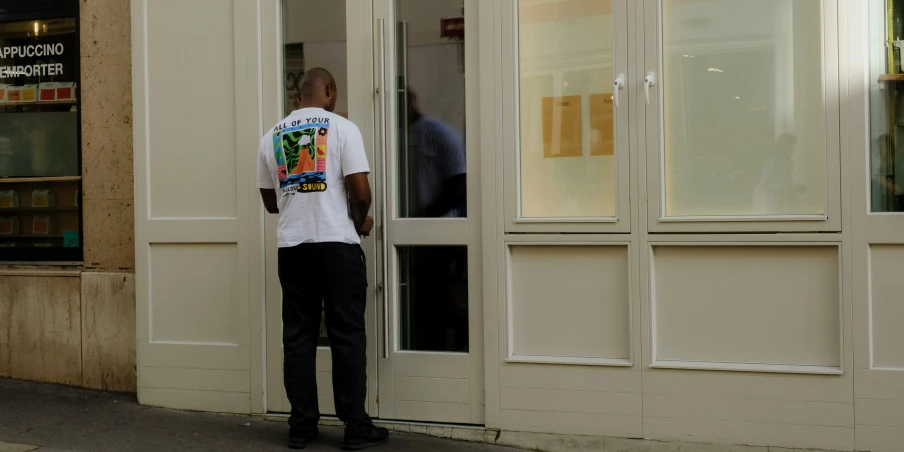 an old man stands by the door of a store