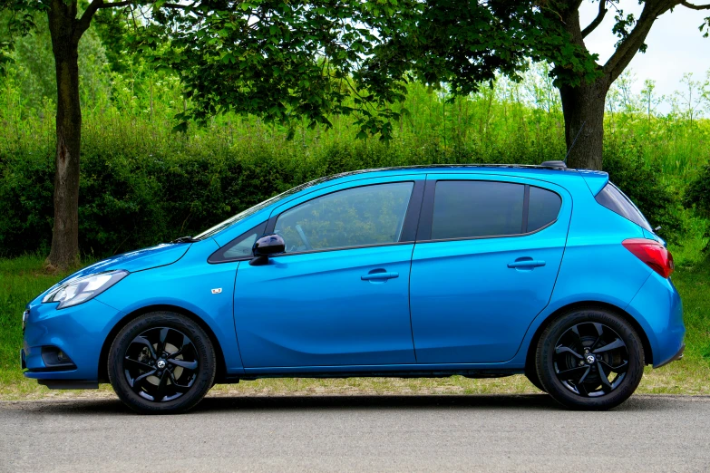 a blue car parked on a roadside next to some trees